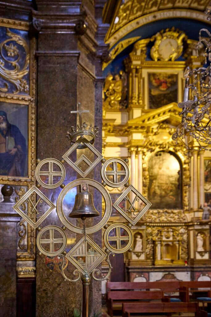 Zlatý liturgický kříž s malým zvonem v historickém kostele